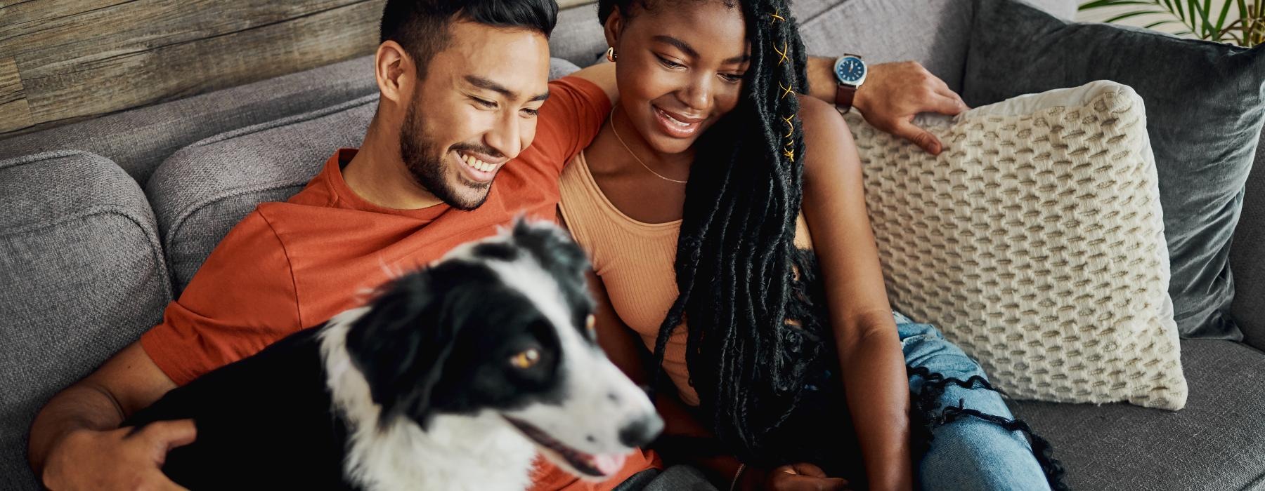 a man and woman sitting on a couch with a dog
