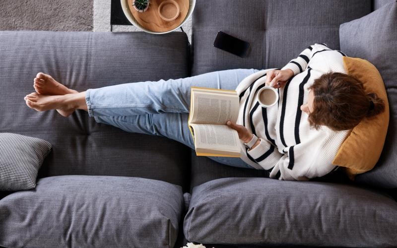 a person lying on a couch reading a book