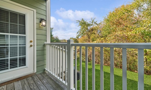 a porch with a railing and a window with trees in the background